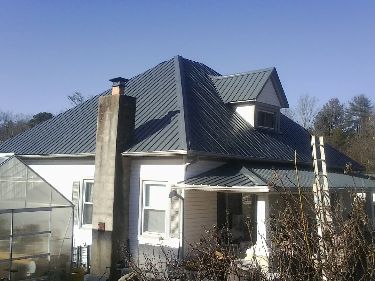 Dark blue standing seam metal roof on a white farmhouse with dormer — Slate & Tile Roof Repair by Roofing Brothers in Mount Hamilton