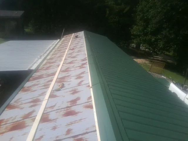 Old rusted panels beside newly installed green metal roofing — Wind Damage Roof Repair by Roofing Brothers in Mount Hamilton