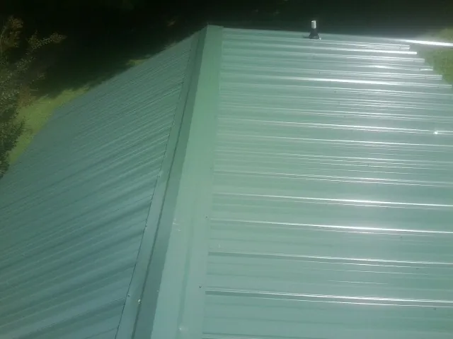 New green metal panels meeting at the ridge of a roof — Flat Roof Repair work by our crew in Mount Hamilton