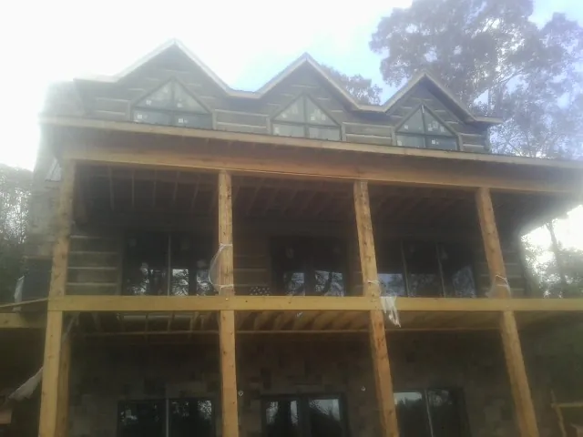 Dormers and porch framing on a large log home under construction — Roof Coating work by our crew in Mount Hamilton