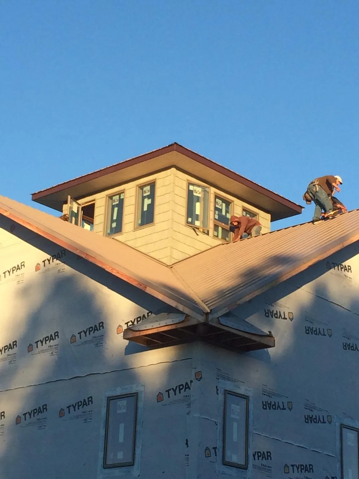 Roofers working around a rooftop cupola on a new metal roof at sunset — Roof Waterproofing in Mount Hamilton by Roofing Brothers